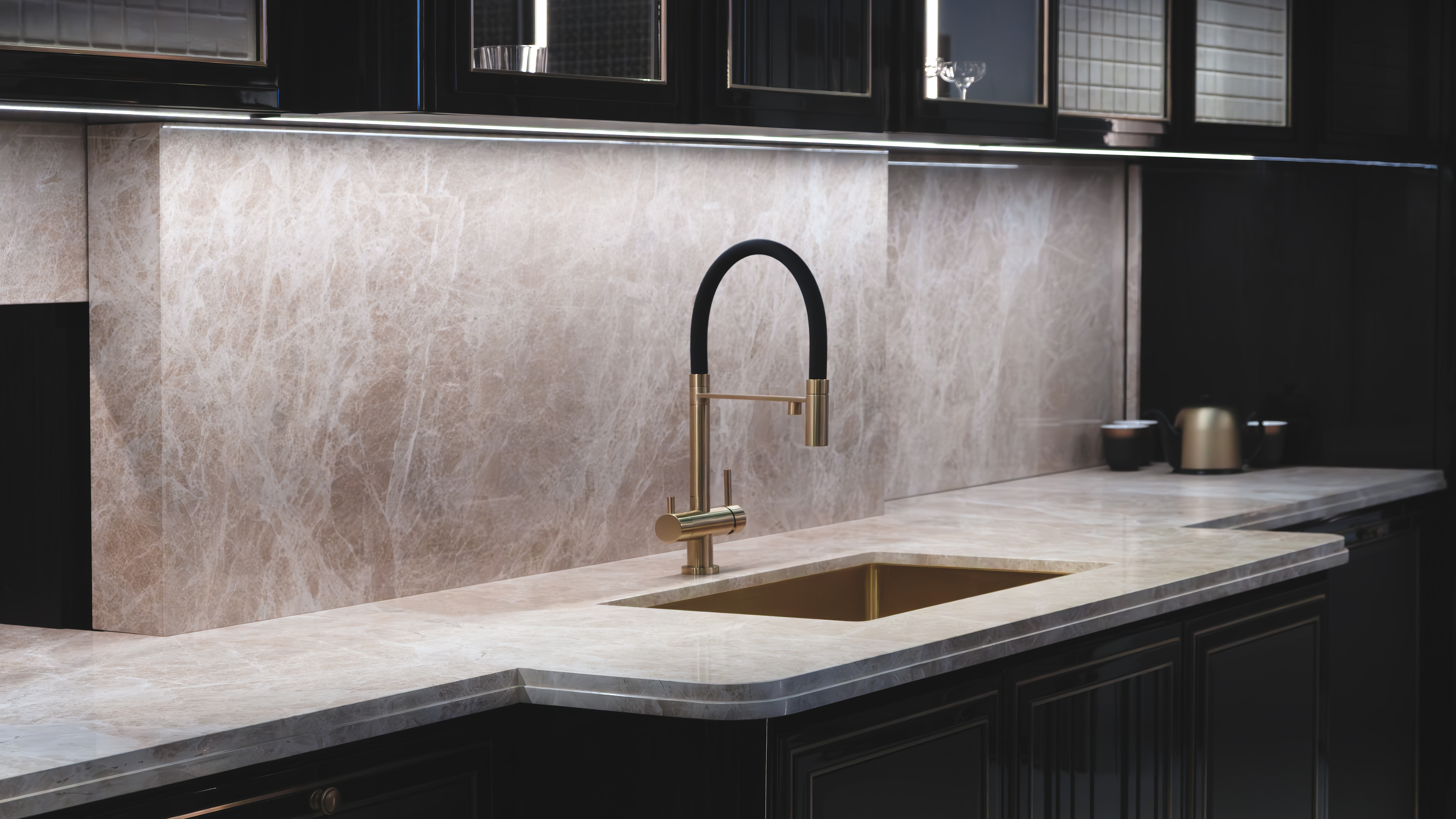 interior-of-a-modern-kitchen-with-a-sink-and-a-faucet-the-sink-is-gold-and-the-faucet-is-black-the-walls-and-countertop-are-beige-marble-the-furniture-is-black